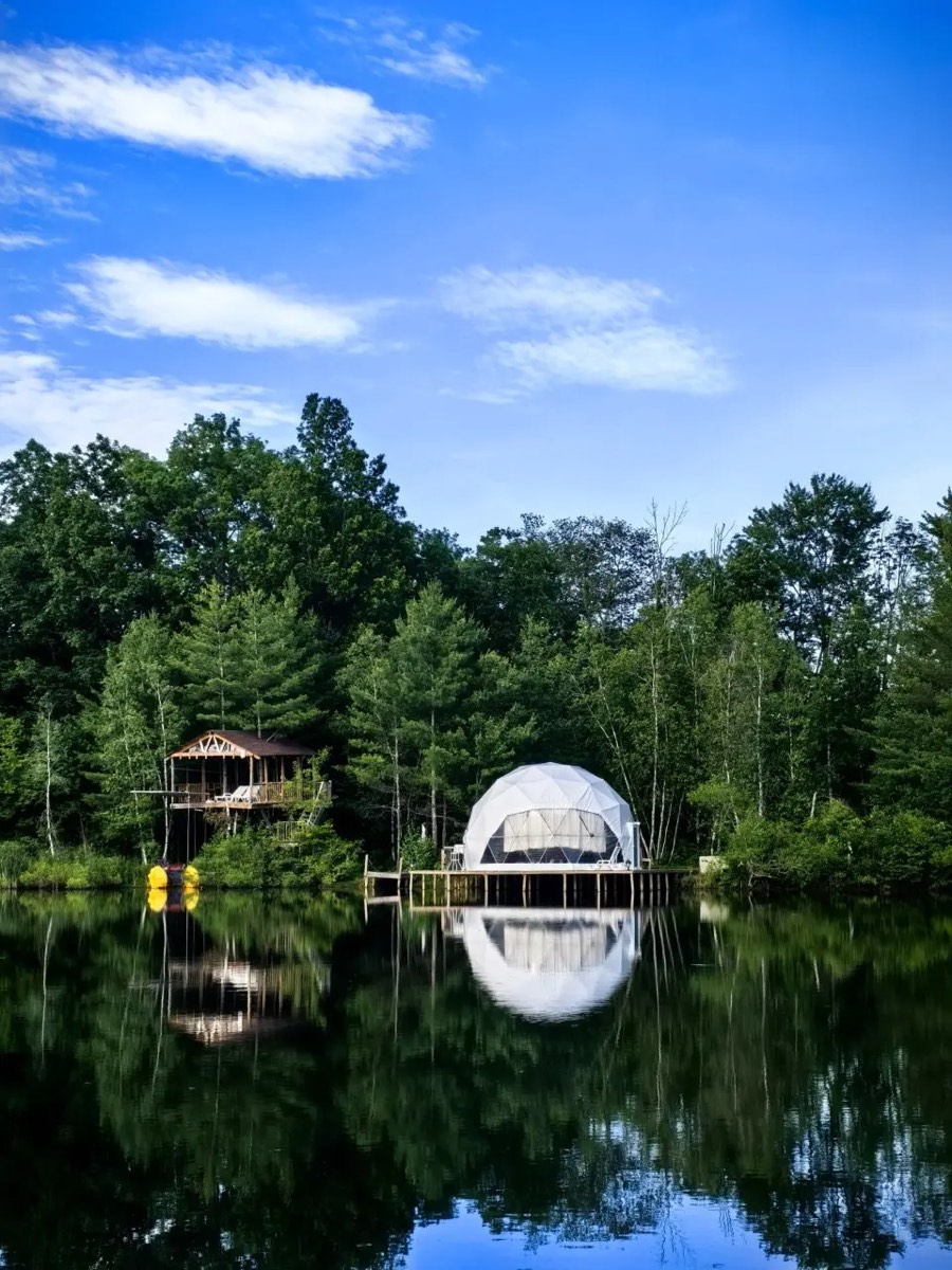 Private lake with a spa dome and cabin reflected in still water near Catskill NY